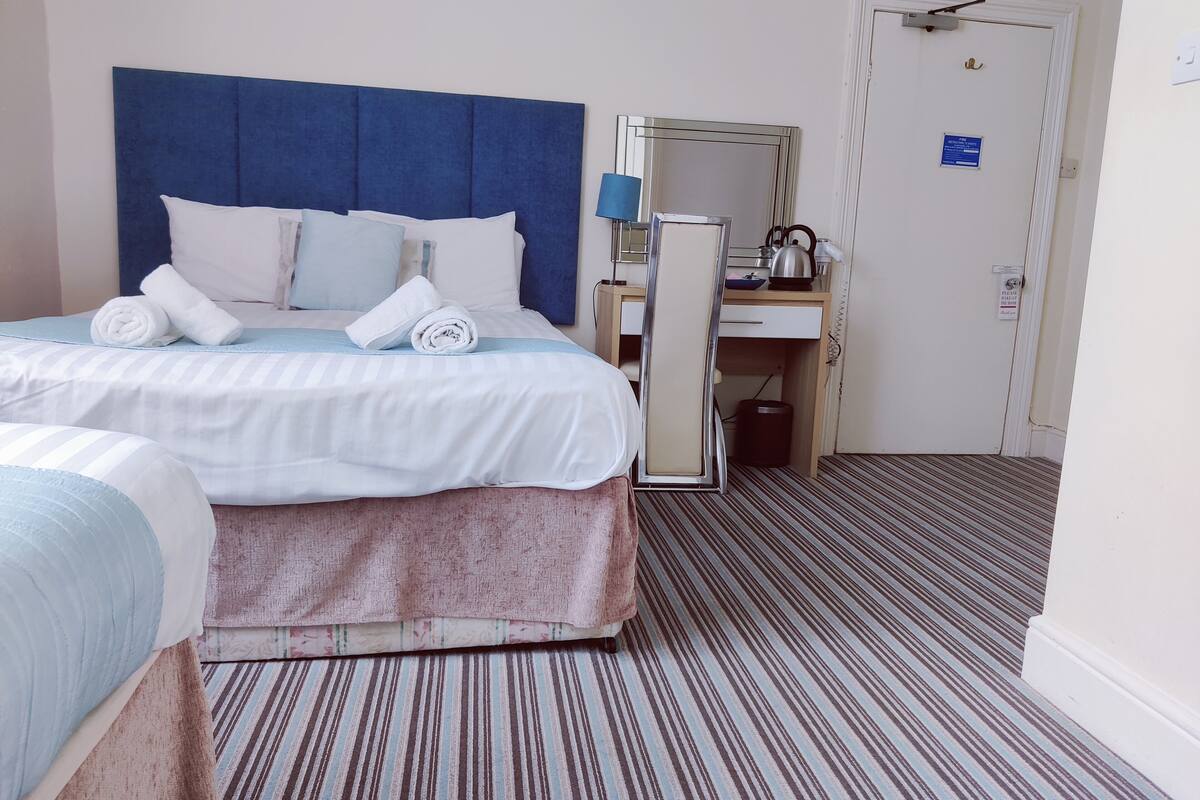 Habitación de hotel con una cama grande, un escritorio, un espejo y una alfombra a rayas.