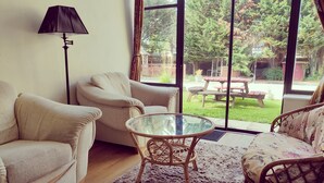 Una sala de estar con una mesa de vidrio, dos sillones, un sofá y una lámpara de pie.