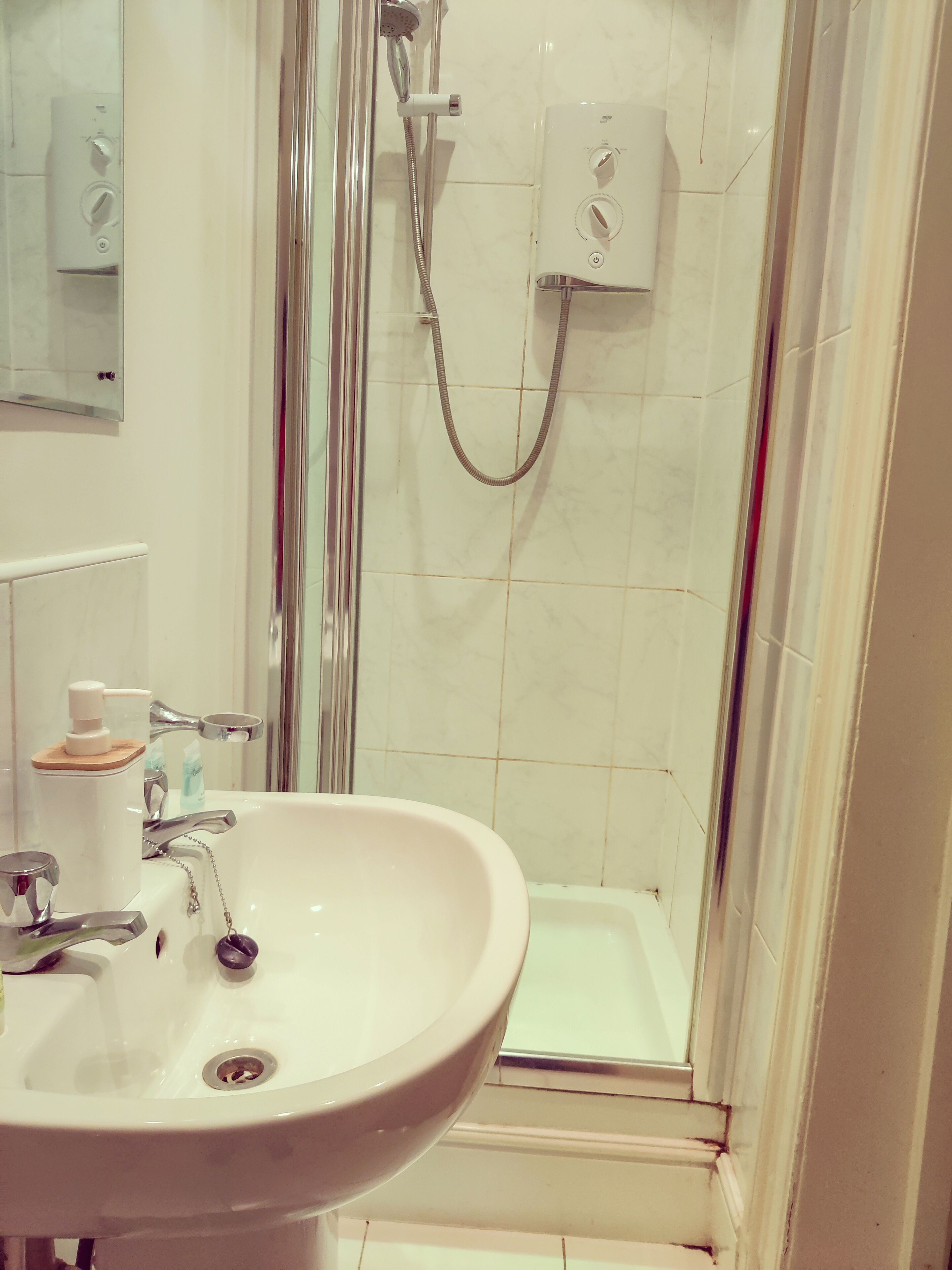 A bathroom with a white sink, a shower with a glass door, and a toilet.