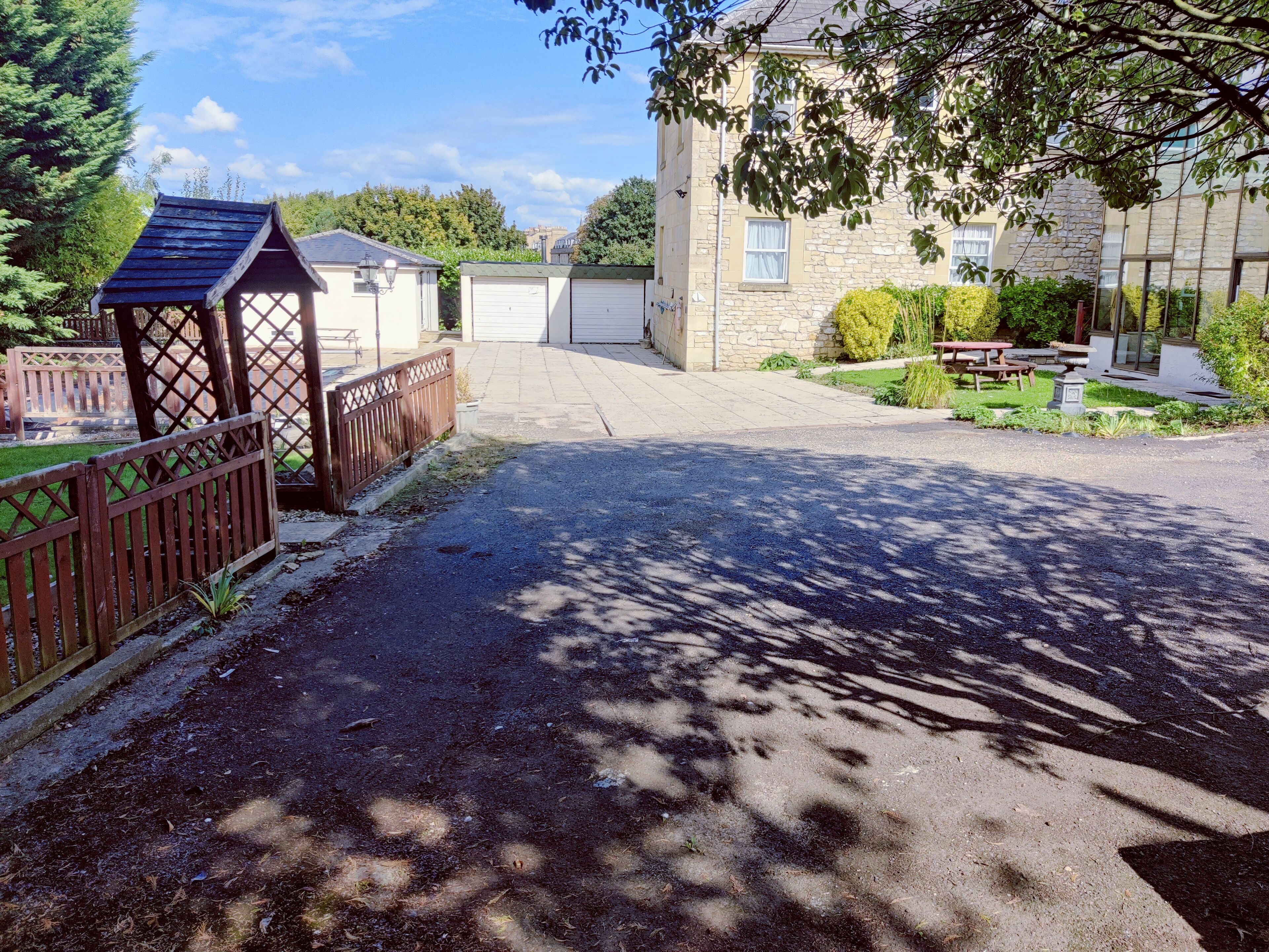 A gated driveway leading to a building with a stone facade and a covered outdoor area.