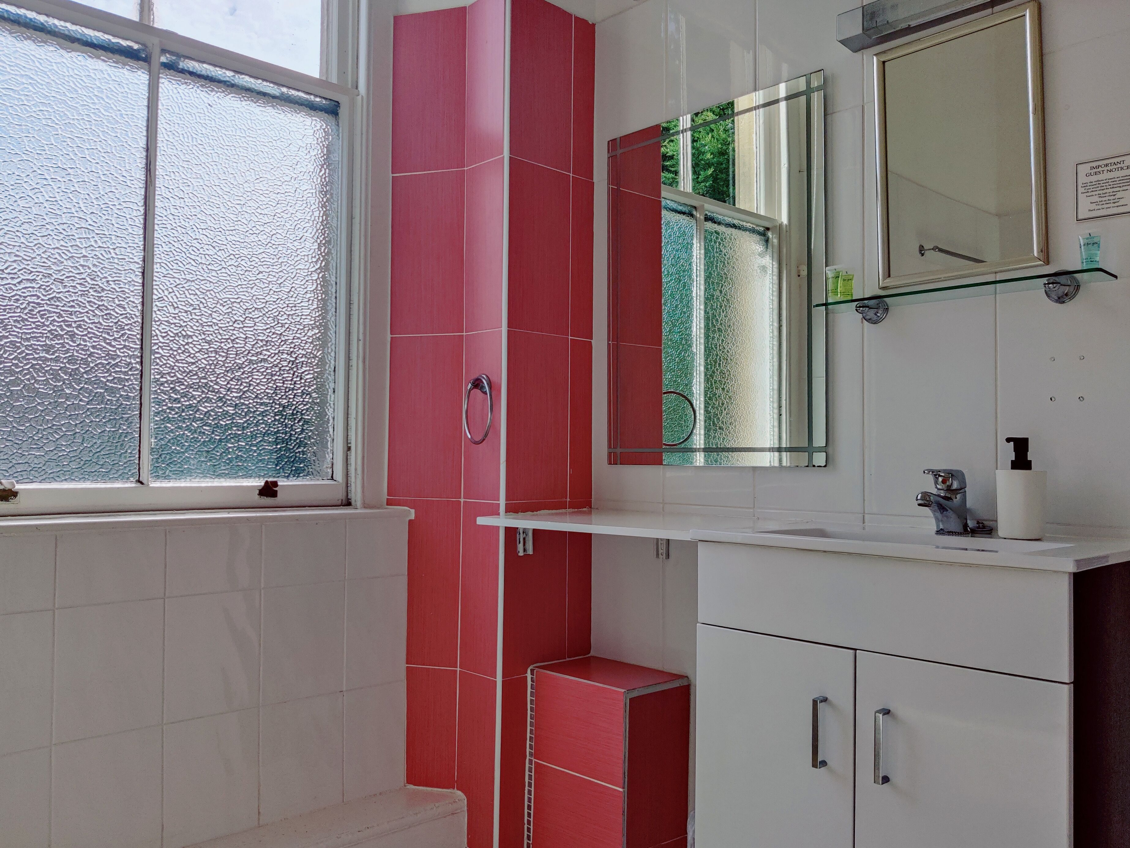 A bathroom with a window, a mirror, a sink, and a toilet.
