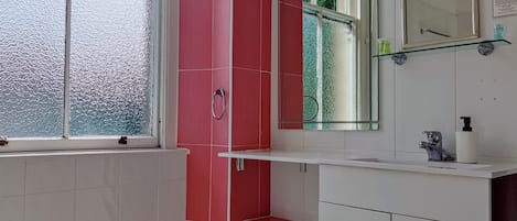 A bathroom with a window, a mirror, a sink, and a toilet.