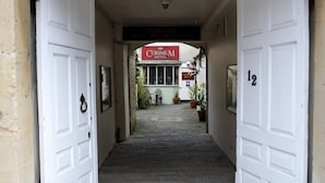 Entrada de hotel con un cartel que dice 'Corinium Hotel' y el número 12 en la pared.
