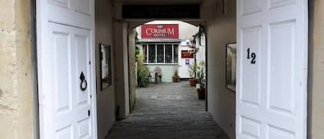 A hotel entrance with a sign for 'Corinium Hotel' and a number '12' on the wall.