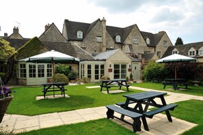 A courtyard with picnic tables and a building with stone walls and pitched roofs. - Corinium Hotel & Restaurant (Cirencester)