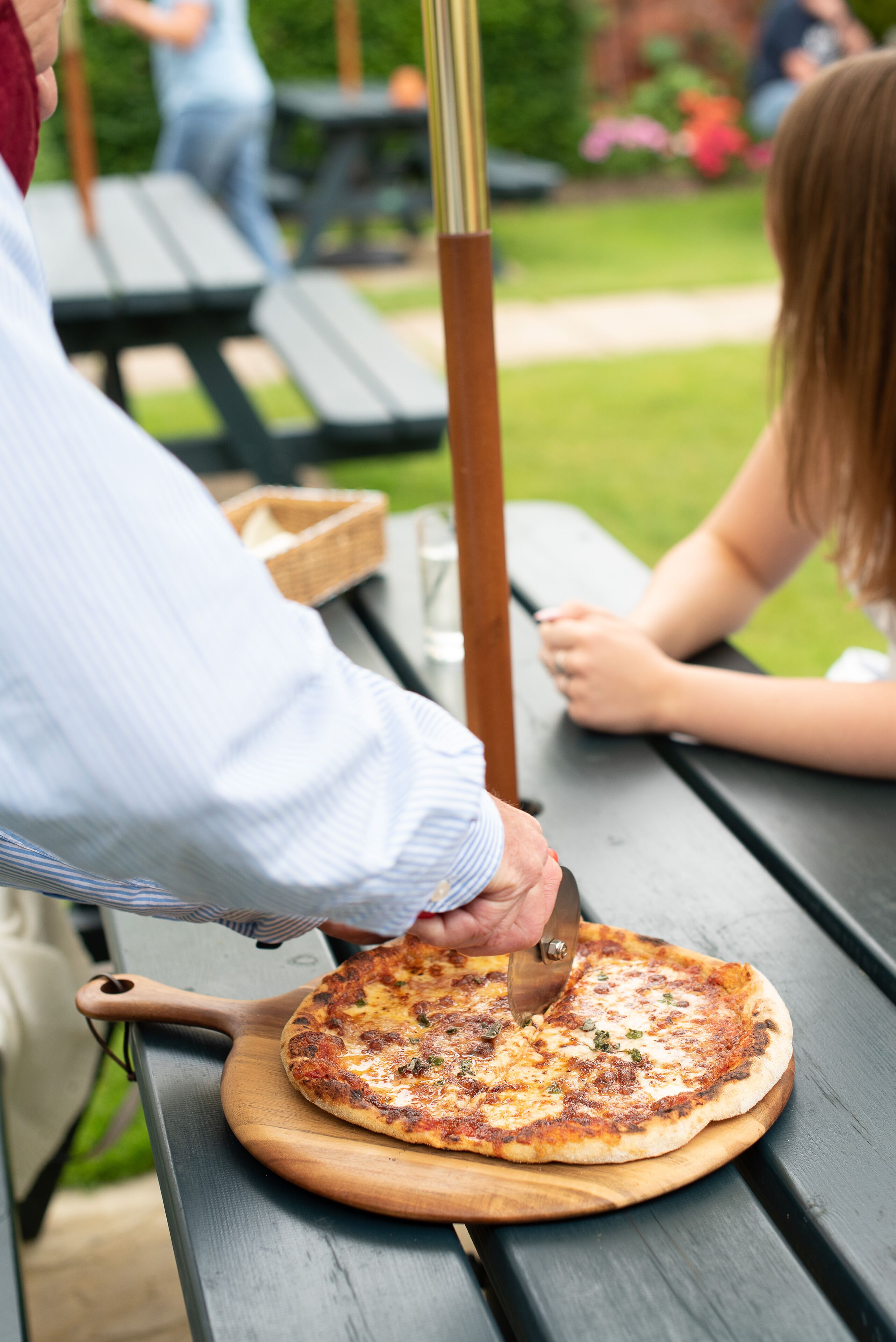 Une pizza sur une planche en bois, posée sur un banc.