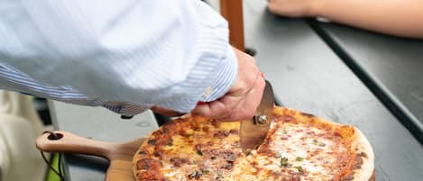Une pizza sur une planche en bois, posée sur un banc.