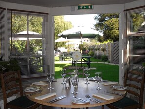 An outdoor dining area with a round table set for a meal, surrounded by wooden chairs. - Corinium Hotel & Restaurant (Cirencester)