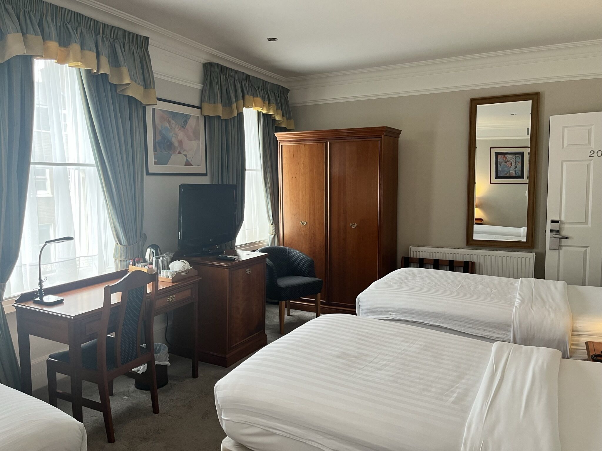 Une chambre d’hôtel comprenant un lit, un bureau avec une chaise, une armoire et un téléviseur.