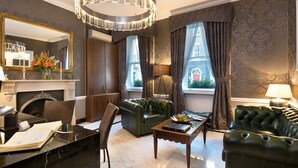 A spacious living room with a fireplace, leather sofas, a coffee table, and a large mirror. - Staunton Hotel (London)