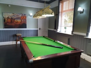 Enjoy a game of pool in this cozy room with a pool table, pool cue, and comfortable seating.