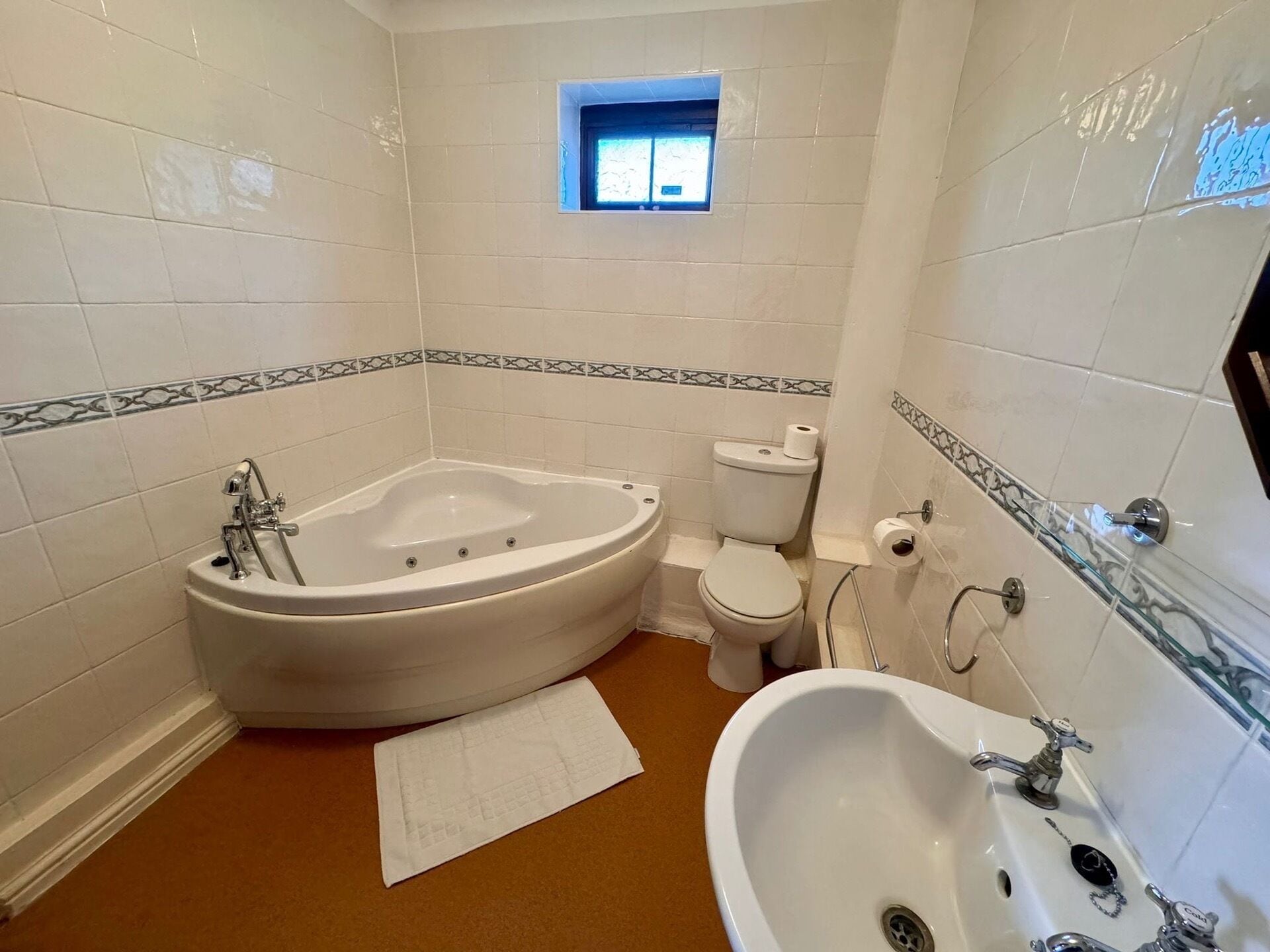 Un baño con una bañera independiente, inodoro, lavabo y un pequeño ventanal.