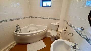 Un baño con una bañera independiente, inodoro, lavabo y un pequeño ventanal.