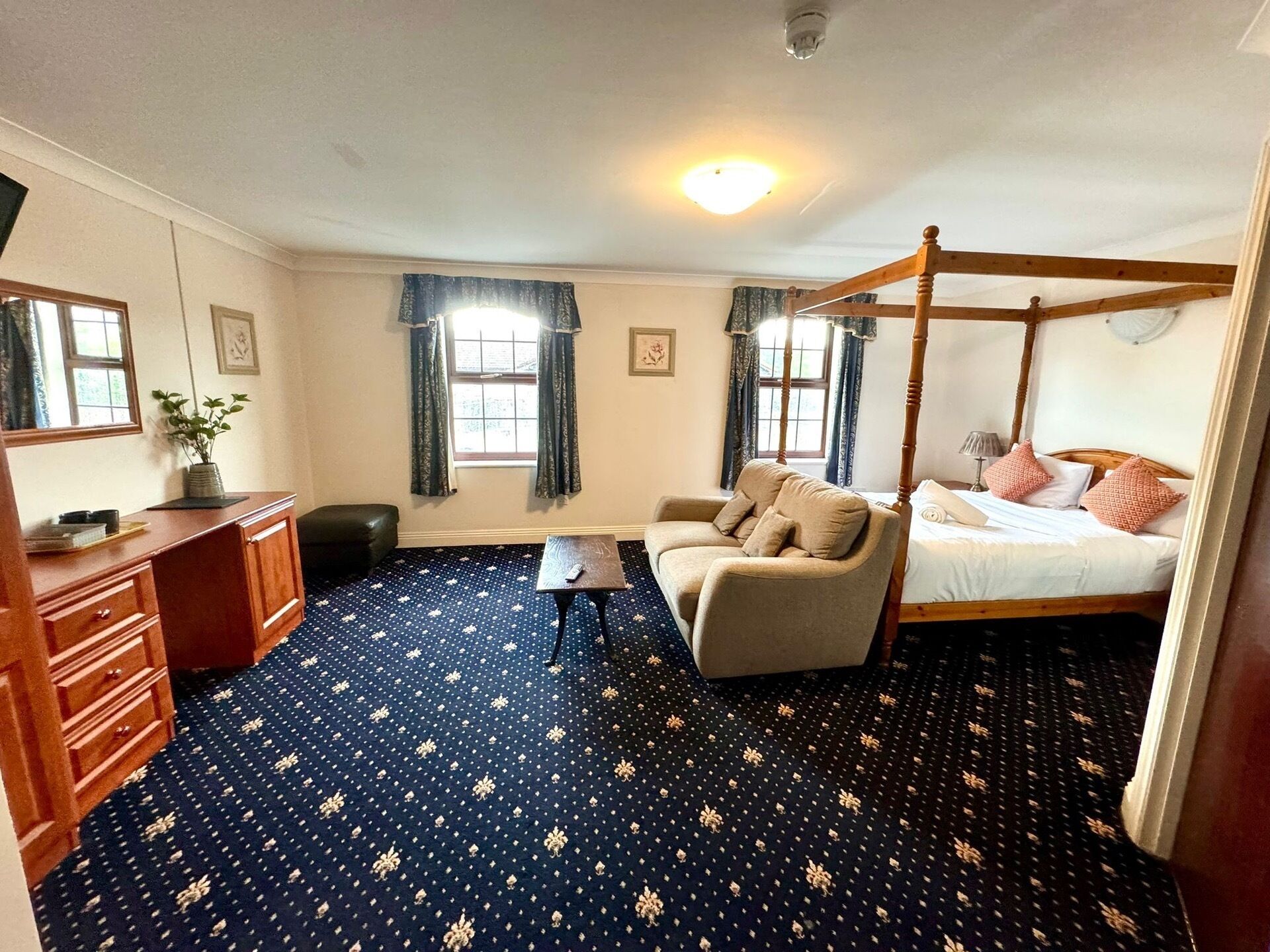A bedroom with a four-poster bed, a sofa, a desk, and a chair.