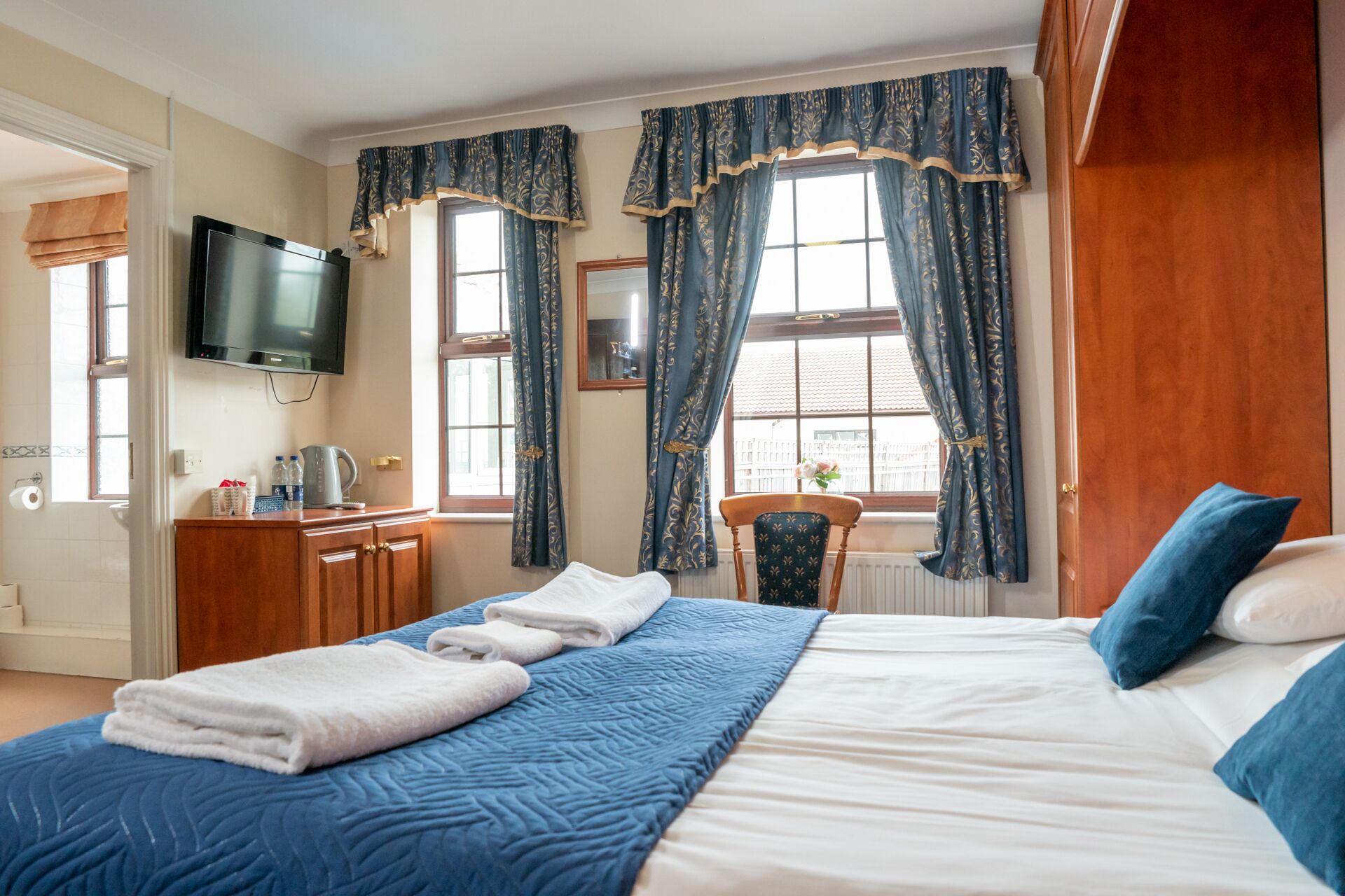 Una camera d'albergo con un letto, una scrivania con televisore e una sedia.