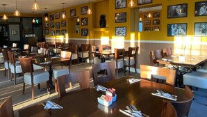 A restaurant with multiple dining tables and chairs, featuring pendant lighting and framed pictures on the walls. - Shurland Hotel (Sheerness)