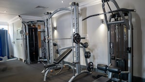 A gym with various exercise machines, a bench, and a door in the background. - Shurland Hotel (Sheerness)
