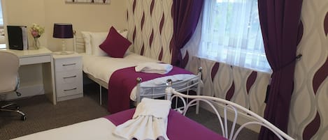 A hotel room with a bed, a desk, a chair, and a window with curtains.