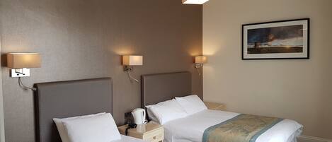 Una camera d'albergo con due letti, ognuno con testiera, comodini e lampade. Sulla parete è appesa una foto incorniciata.