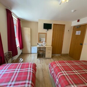 A room with two beds, a desk, a chair, a television, and a wardrobe. - Seven Dials Hotel (London)