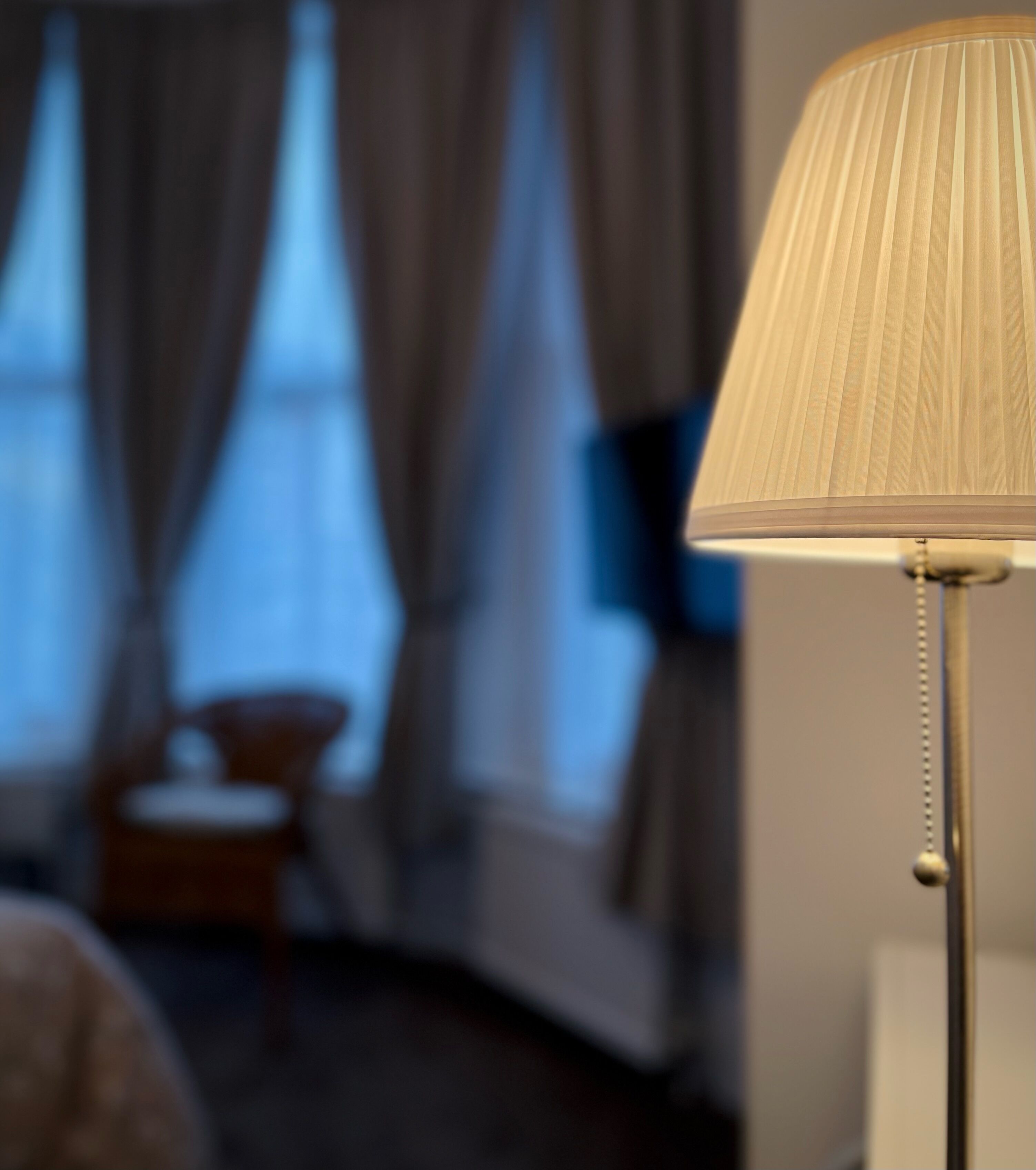 A close-up of a lamp with a pleated shade in a room.