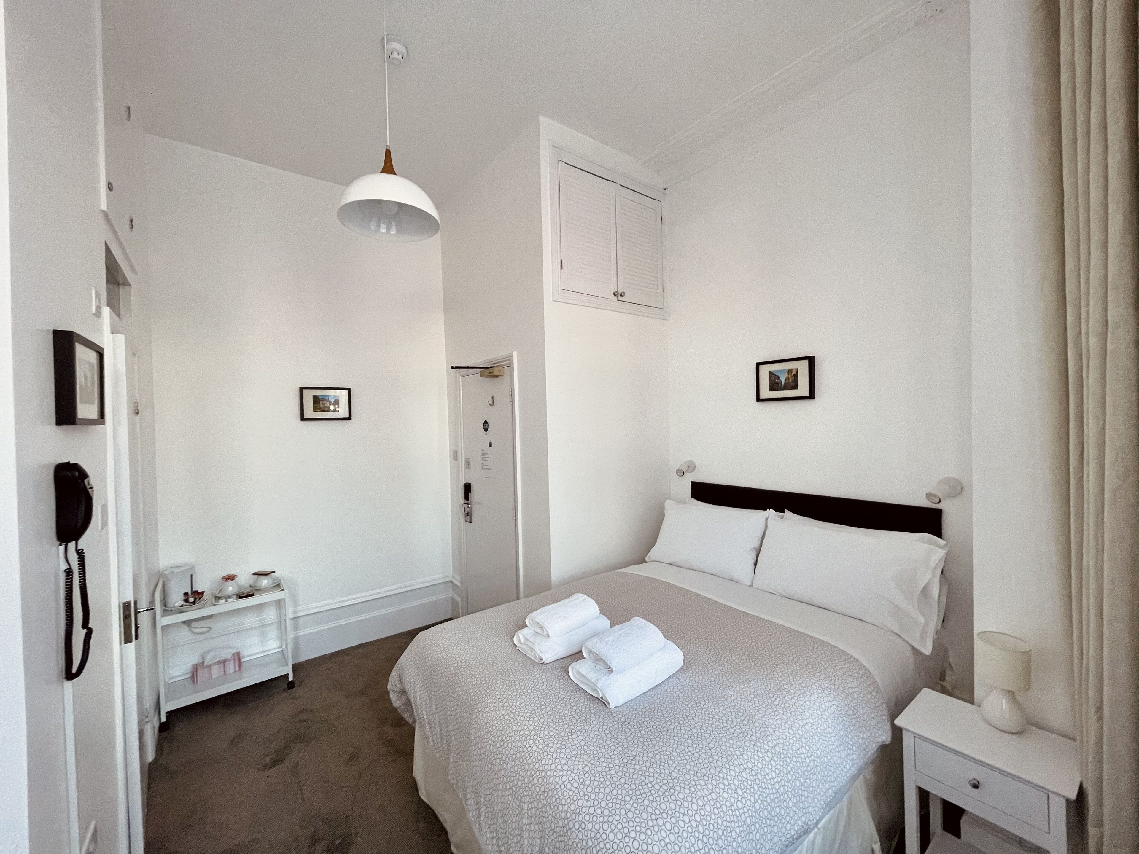 Un dormitorio con cama, mesita de noche y lámpara colgante.