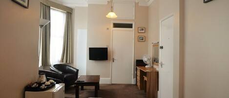 A hotel room with a bed, a desk, a chair, a television, and a mirror.