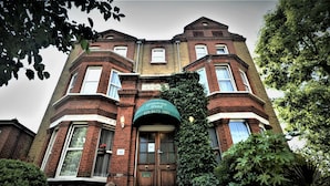 A Victorian-style hotel with a prominent entrance, a green awning displaying the name and contact number, and a brick facade with large windows and a bay window on the second floor. - Gateway Hotel (London)