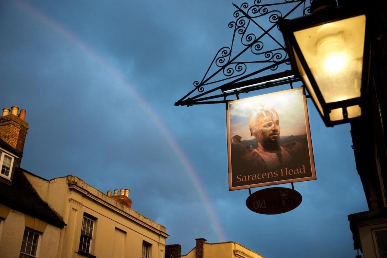 A building with a sign reading "Saracens Head" and a rainbow in the background.