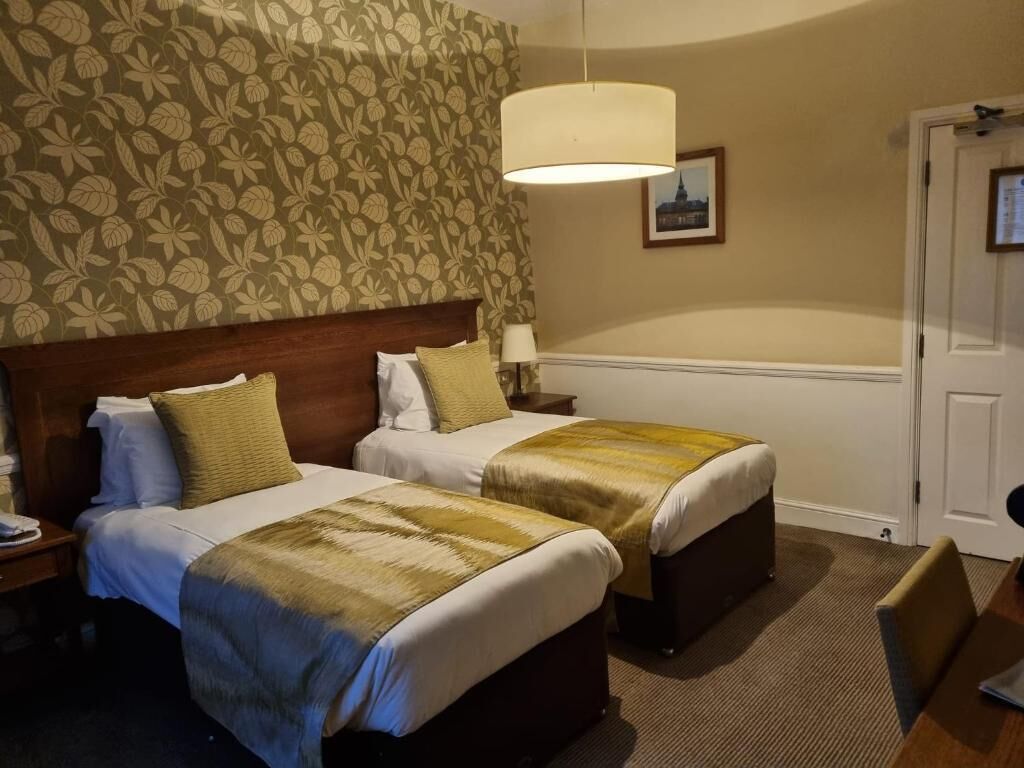 Ein Hotelzimmer mit zwei Betten, einem großen Fenster und einer Tür.