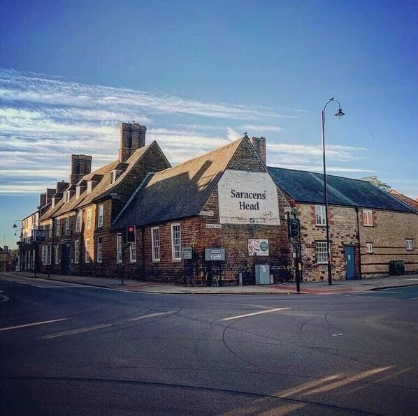 A traditional brick building with a sign reading "Saracens Head." - Saracens Head Towcester by Greene King Inns (Towcester)