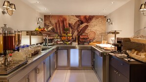 A modern kitchen with a central island, equipped with various appliances and a fruit display. - Paddington Court Rooms (London)