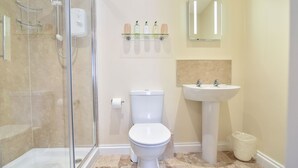 A bathroom with a glass shower enclosure, a toilet, a sink, and a mirror. - The Europa (Whitby)