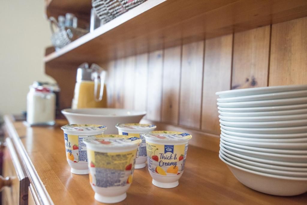 A kitchen counter with yogurt cups, a glass pitcher, and stacked plates.