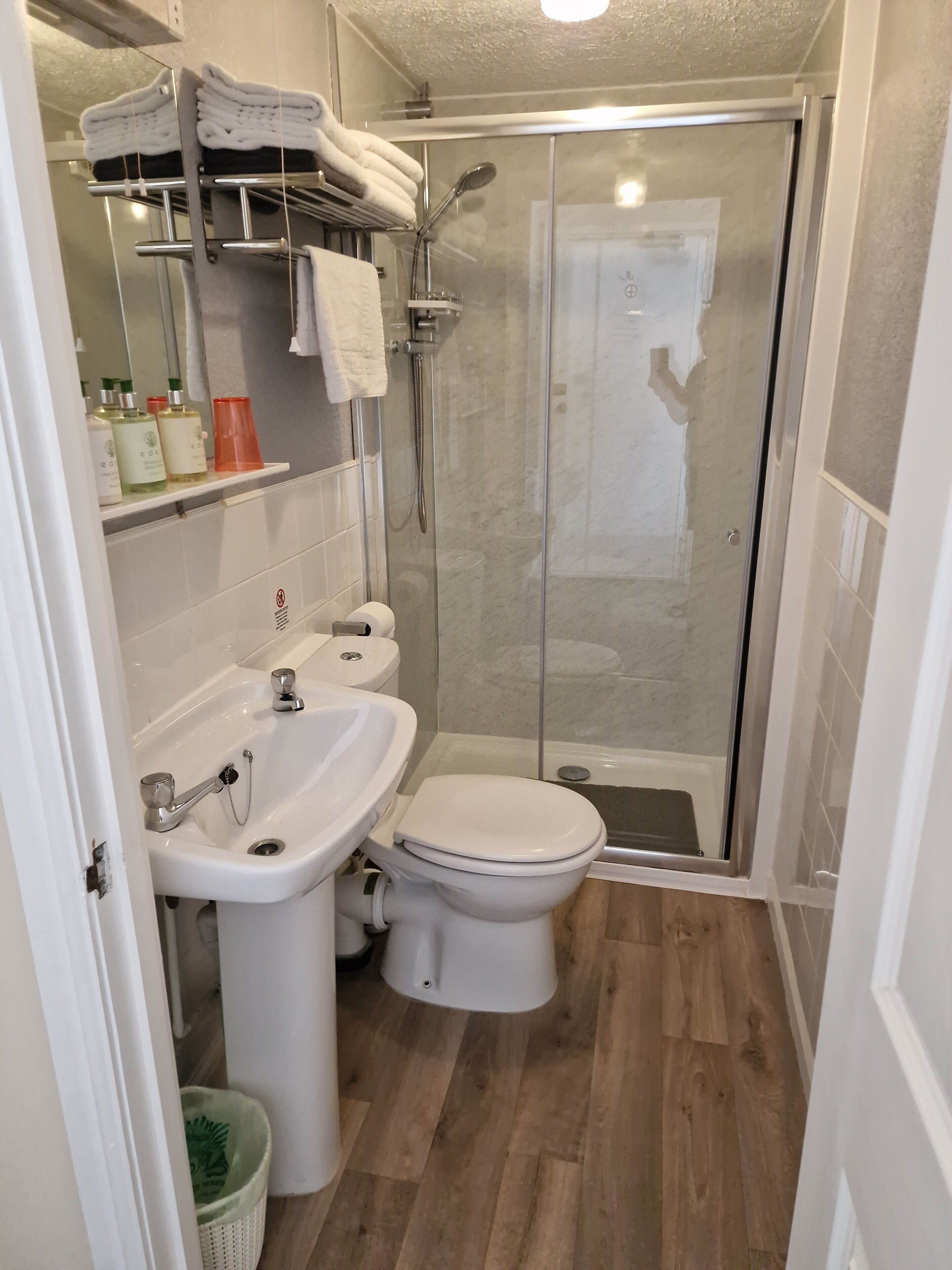 A bathroom with a shower, toilet, sink, and a mirror.
