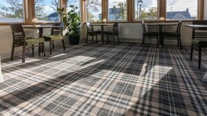 A room with a checkered carpet, large windows, and a potted plant. - Castletown Hotel (Thurso)