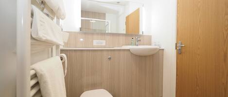 A modern bathroom with a toilet, sink, and mirror.