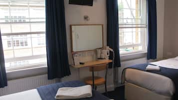 A hotel room with two beds, a desk, a mirror, a TV, and a window with curtains.