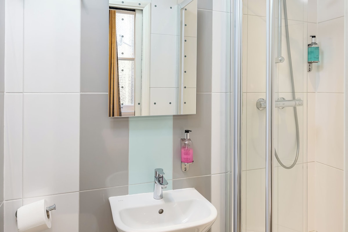 A bathroom with a shower, sink, toilet, and a mirror cabinet.