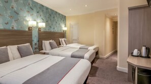 A hotel room with two beds, a wooden headboard, a wall with a butterfly pattern, and a small kitchenette with a kettle. - OYO Bakers Hotel London Victoria (London)