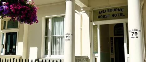 The entrance of Melbourne House Hotel with a sign indicating the address and name.