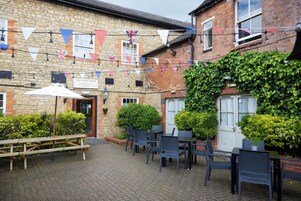 Un edificio de piedra con un letrero que dice "The Coach House" y un patio con mesas y sillas.
