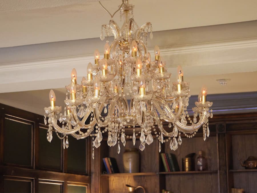 Un candelabro con múltiples luces y adornos de cristal en una habitación con paneles de madera y estanterías.