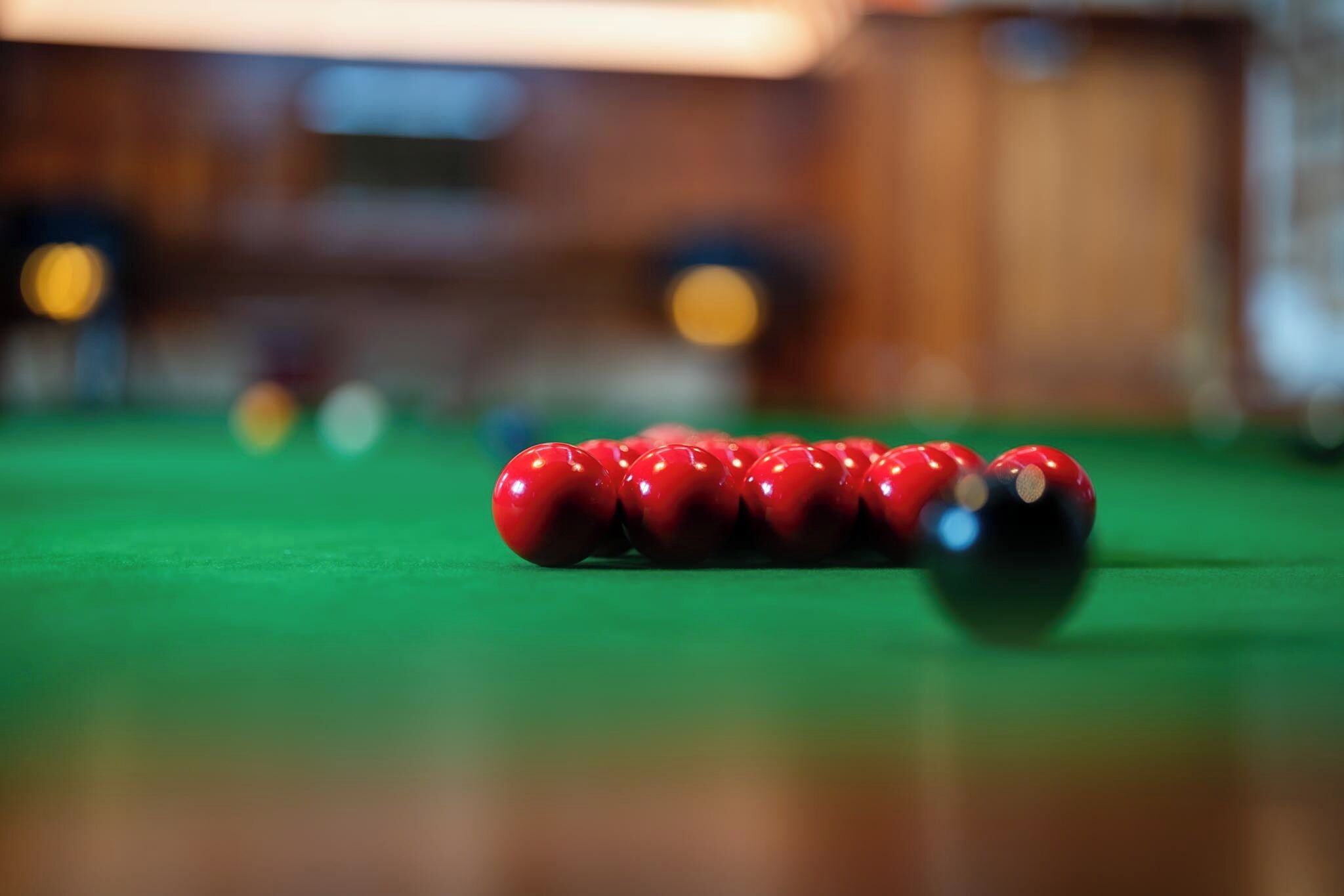 Een close-up van een pooltafel met rode en zwarte ballen.