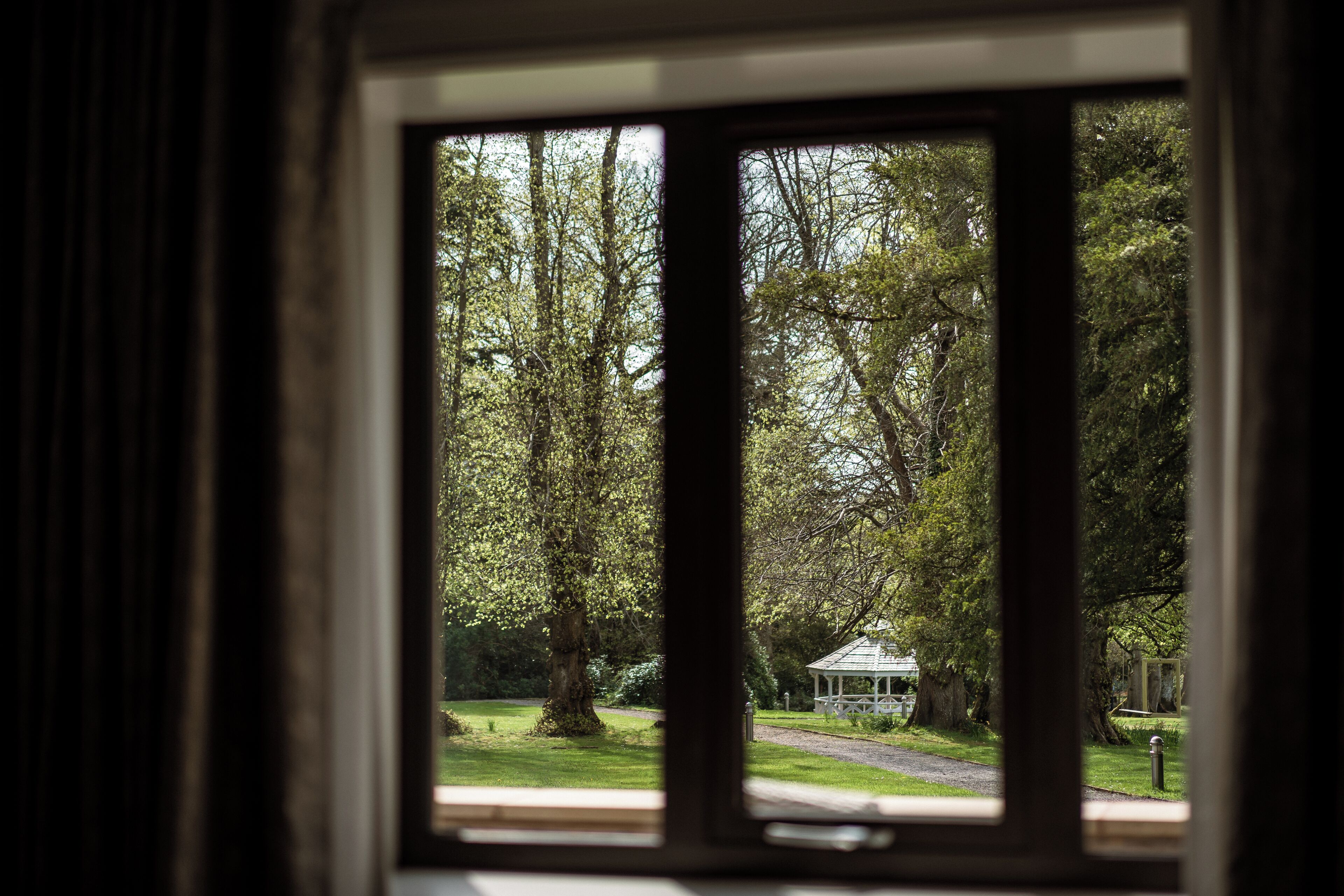 A view through a window of a park with a gazebo.