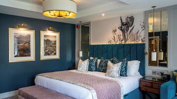 Un dormitorio con una cama grande, un banco, una mesita de noche, un espejo y decoración en la pared.