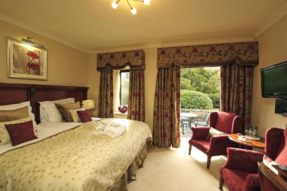 A hotel room with a large bed, a desk with a chair, a television, and a view of the outdoors.