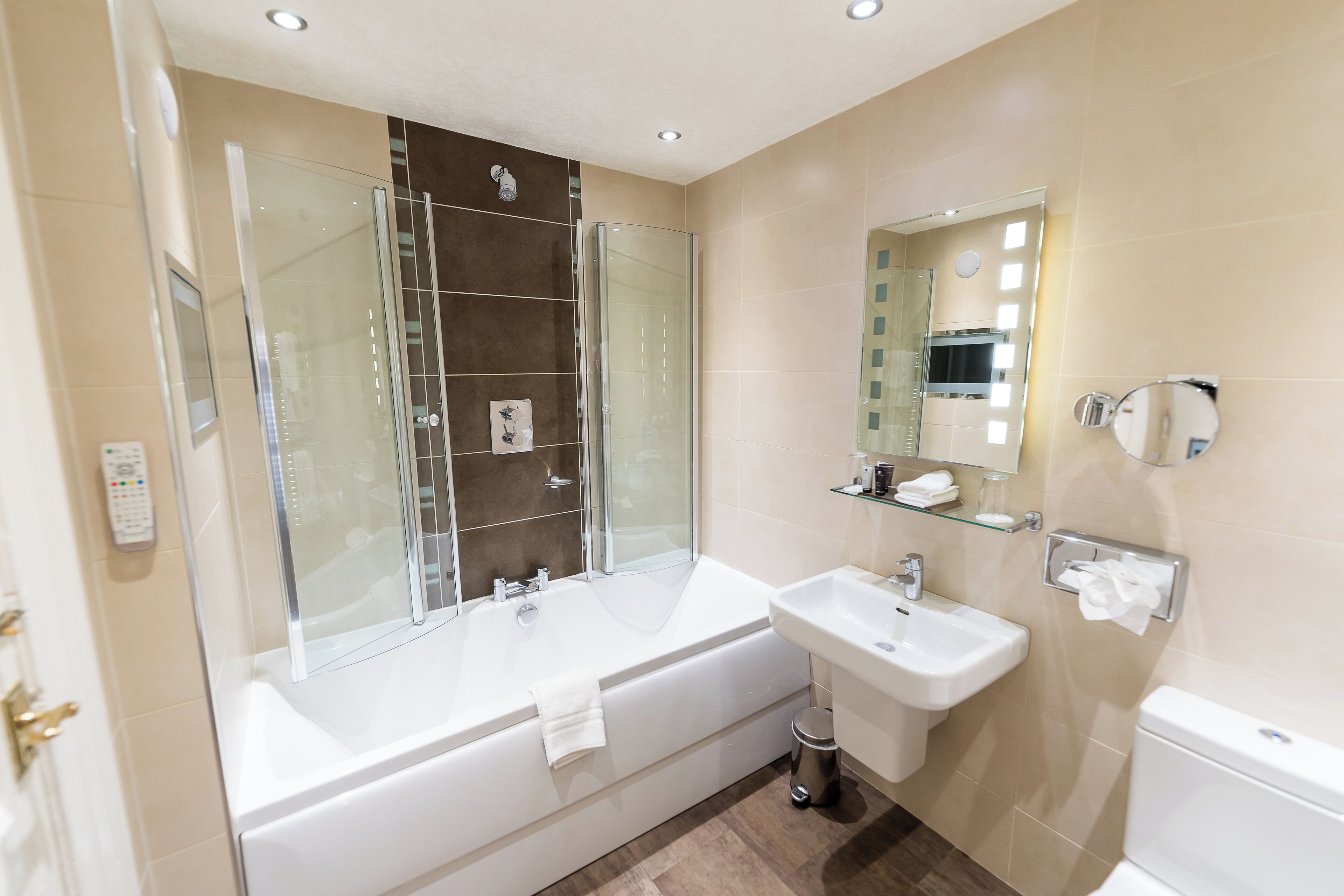 A modern bathroom with a glass-enclosed shower, a large bathtub, a sink, and a toilet.