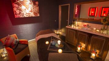 Relax in a serene spa room with a comfortable seating area, massage table, and modern vanity.