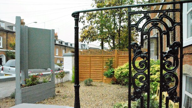 A gated entrance with a metal gate and a wooden fence. - Bow Guest House (Reading)